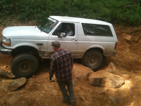 2005 Jeep Wrangler - White Ford Bronco tackling a challenging off-road course with large rocks.