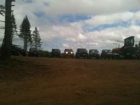 2005 Jeep Wrangler - A group of Jeeps are lined up on a dirt path, with a large bulldozer visible to the right.