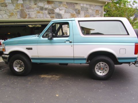 1994 Ford Bronco - Side view of a two-tone teal and white Ford Bronco.