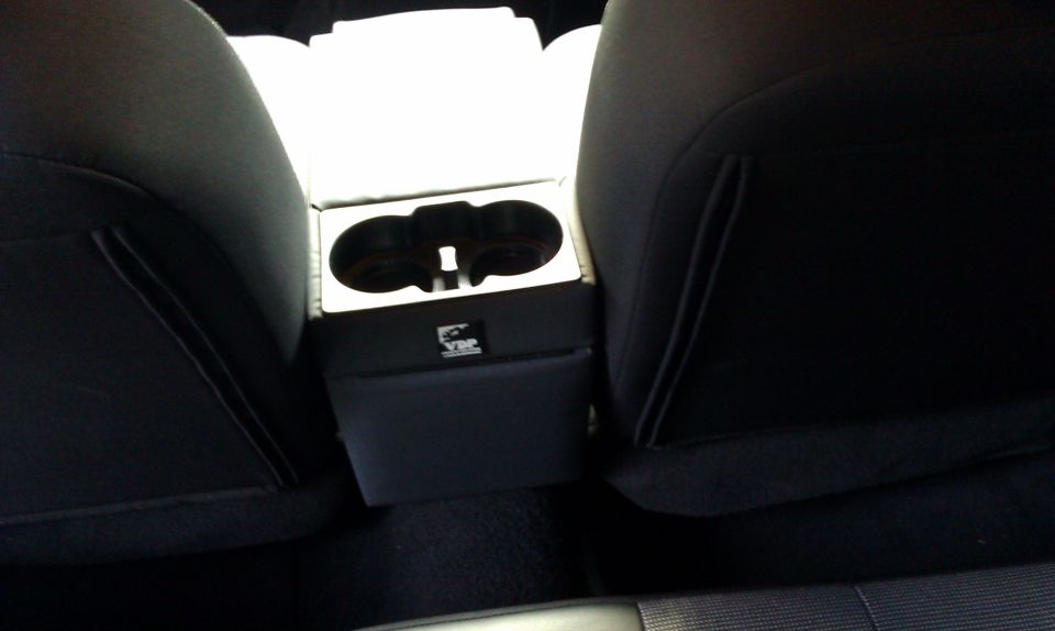 Center console with dual cup holders and a VIP logo, viewed between car seats