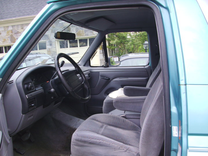 Teal SUV interior, showing grey cloth seats, dashboard, and steering wheel. Exterior visible through windows