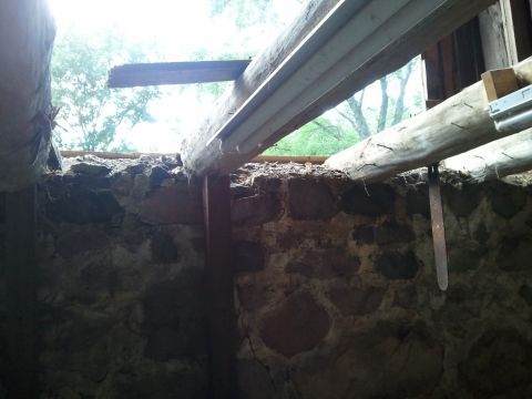 1985 Ford F-150 - Looking up through an opening in a stone structure, revealing wooden beams and trees outside.