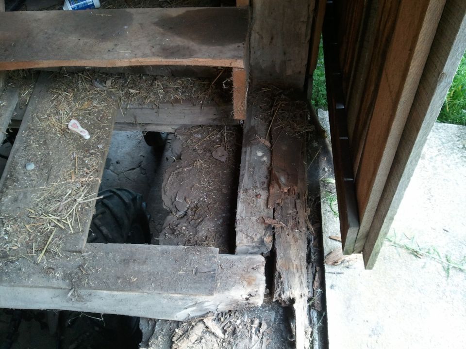 Tire visible through hole in weathered wooden floorboards