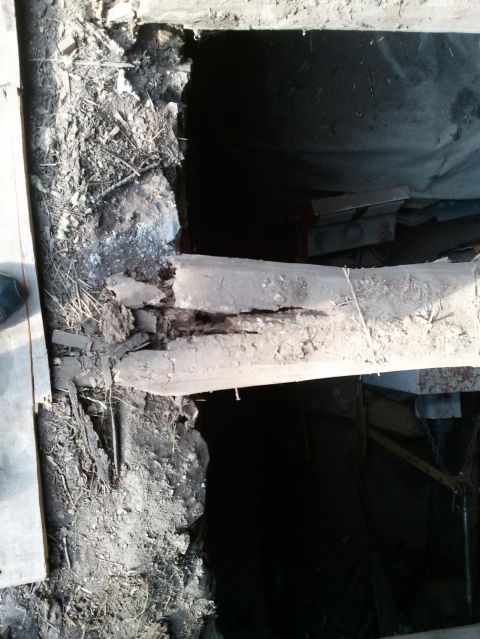 1985 Ford F-150 - A close-up view of a broken wooden beam and surrounding debris, with a dark opening behind it.