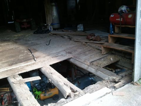 1985 Ford F-150 - The floor of this barn is in disrepair, revealing items stored beneath the damaged planks.