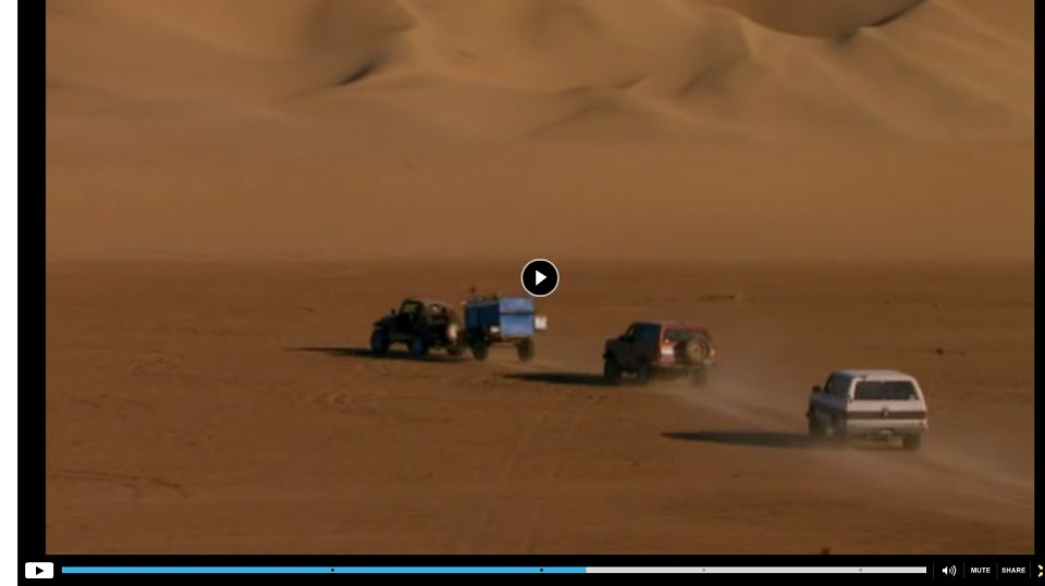 Three off-road vehicles driving in a desert landscape with sand dunes