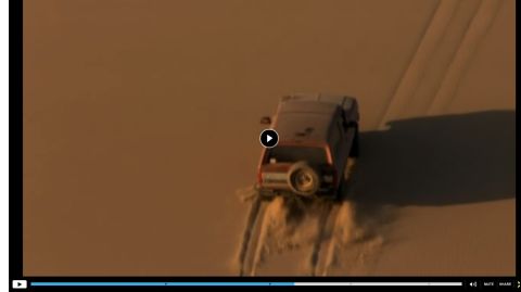1994 Ford Bronco - An SUV navigates a sandy terrain, leaving tracks in its wake.