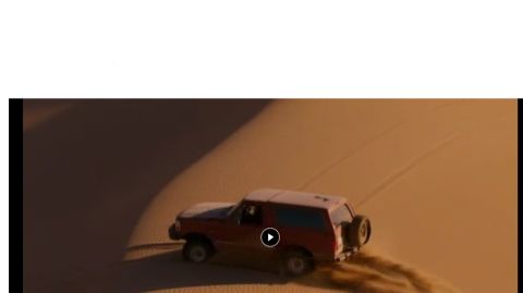 1994 Ford Bronco - A red SUV navigates sandy terrain, leaving tire tracks behind.