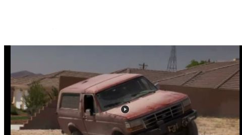 1994 Ford Bronco - Video still with a play button overlay showing a weathered red full-size Ford Bronco with a removable hardtop climbing a dirt berm in a des…