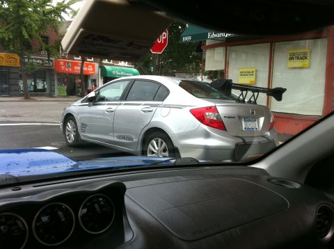 2007 Subaru Impreza - Silver sedan with a large rear spoiler and racing stripes is parked on a city street.