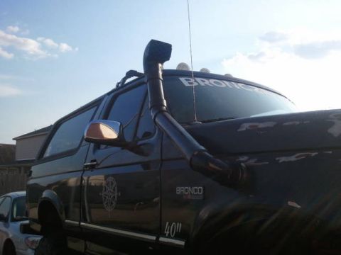 1995 Ford Bronco - A dark Ford Bronco is seen from a 3/4 front angle, equipped with a snorkel and roof rack.