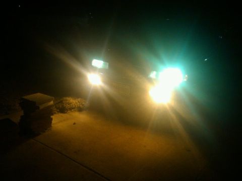 1996 Mercury Grand Marquis - A car's headlights illuminate the dark scene, casting bright beams.