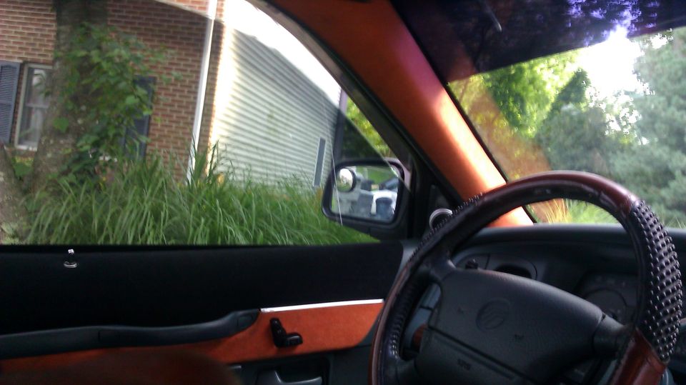 Interior view of car with wood-trimmed steering wheel and orange trim