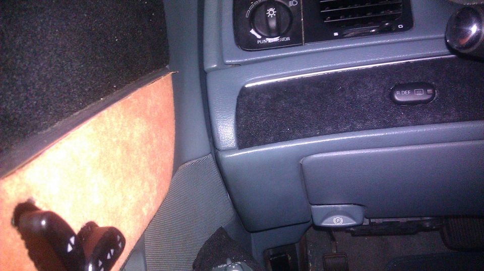 Car interior dash with headlight control and rear defogger button. Part of a person's leg is visible on the left