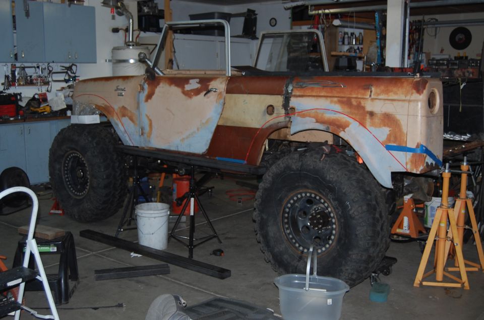 Rusty 1961 International Scout 800 body with large tires, undergoing modifications