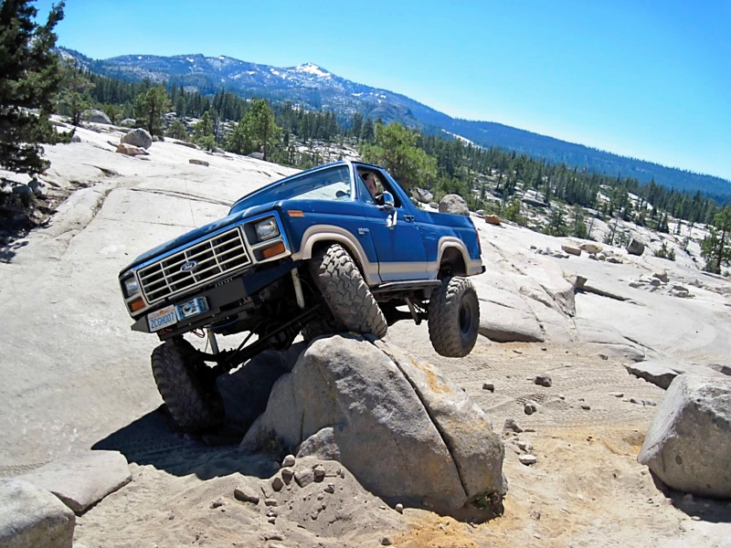 Blue Ford Bronco climbing over rocks on a trail