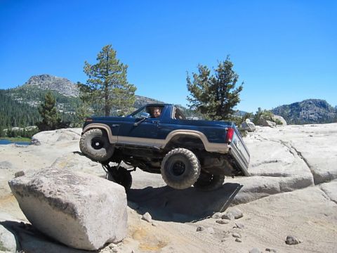 1986 Ford Bronco - This modified SUV is navigating a rocky trail with one wheel in the air.