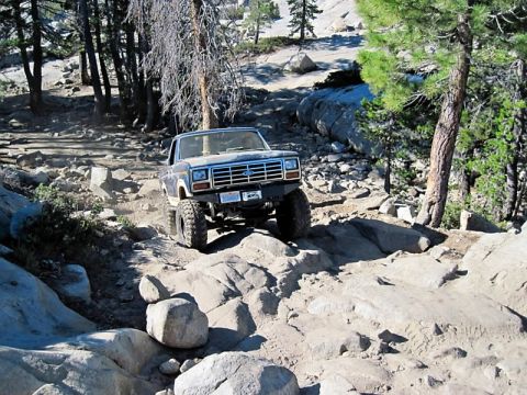 1986 Ford Bronco - This Ford Bronco navigates a rocky off-road trail, kicking up dust as it goes.