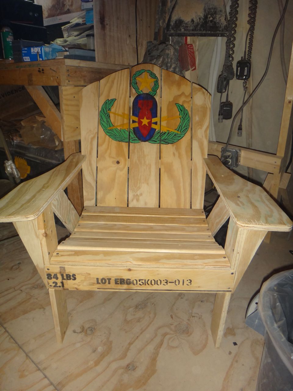 Wooden Adirondack chair with military insignia on backrest and stenciled lot number on seat base