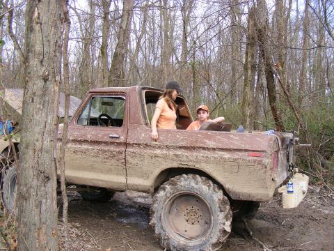 1978 Ford Bronco - Two people are in a muddy 1978 Ford Bronco, parked in a wooded area.