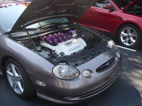 1992 Ford Taurus - A modified Ford Taurus with its engine exposed, parked next to another Taurus at a car show.