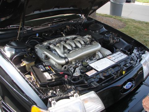 1992 Ford Taurus - The engine bay of a black 1992 Ford Taurus is open, revealing the V6 engine and associated components.