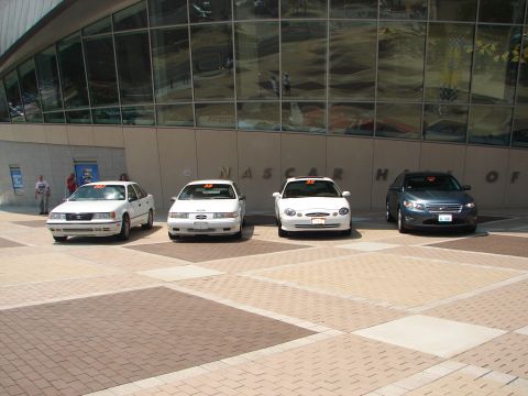 1992 Ford Taurus - A lineup of four cars, including a 1992 Ford Taurus, are parked outside the NASCAR Hall of Fame.