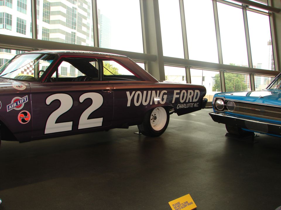 Purple race car with number 22 and 'YOUNG FORD' text, next to a blue car
