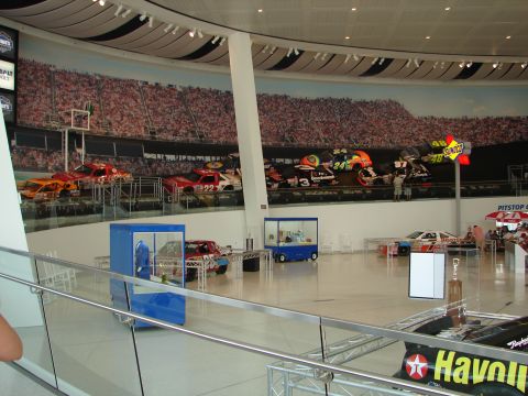 1992 Ford Taurus - This indoor display features several race cars and a large mural depicting a crowded stadium.