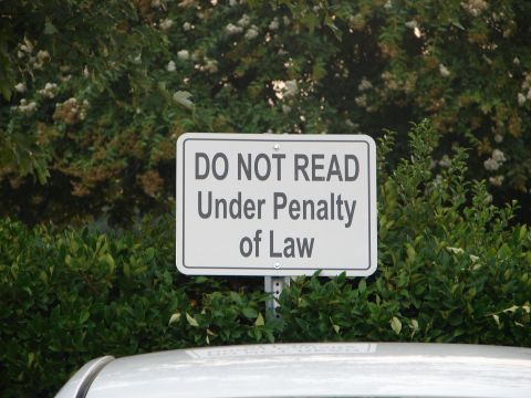 1992 Ford Taurus - A sign warns against reading it, with foliage and a vehicle roof in the foreground.