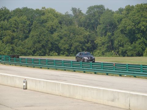 1992 Ford Taurus - A Pontiac G8 is seen on a race track with a green barrier in the foreground and trees in the background.