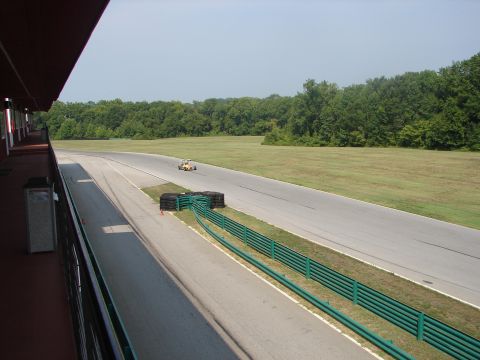 1992 Ford Taurus - A go-kart races on a track, with a grandstand on the left and trees lining the course.