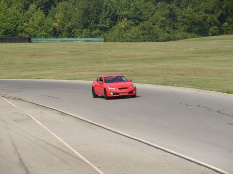 1992 Ford Taurus - Red coupe driving on a race track with trees and grass in the background.