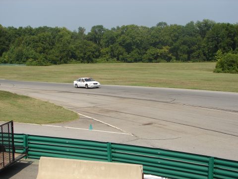 1992 Ford Taurus - A white 1992 Ford Taurus drives on a racetrack during an event.