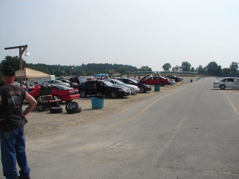 1992 Ford Taurus - A gathering of vehicles is seen parked on a sunny day, with a person observing from the side.