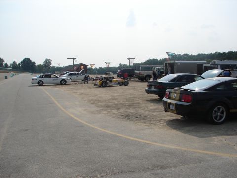 1992 Ford Taurus - Cars and support vehicles are gathered on the pit lane of a race track.