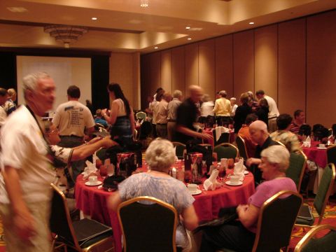1992 Ford Taurus - Attendees mingle and sit at tables during a convention event, with a projector screen visible in the background.