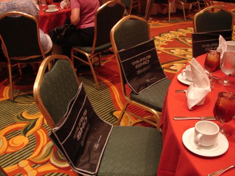1992 Ford Taurus - Bags with 'Taurus SHO' text are placed on chairs at a table set for a meal.