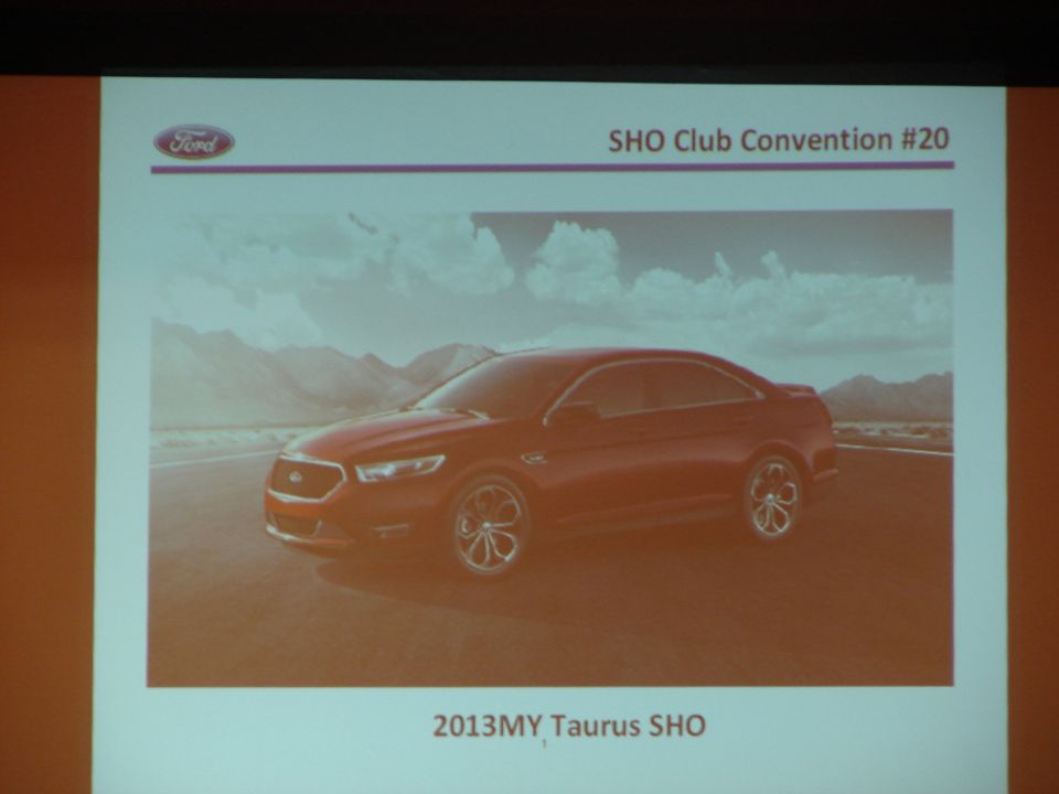 Red 2013 Ford Taurus SHO sedan parked on a road with mountains in the background