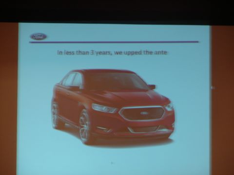 1992 Ford Taurus - A red Ford Taurus is shown on a projection screen with text about improving the vehicle.