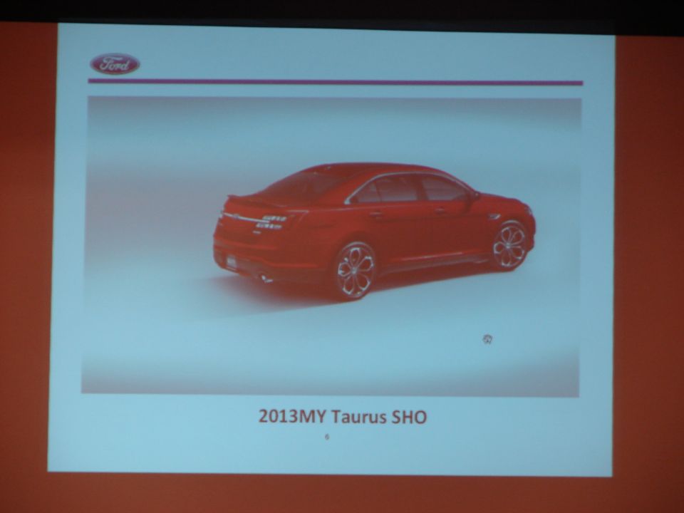 Red sedan, rear three-quarter view, with distinctive wheels and spoiler