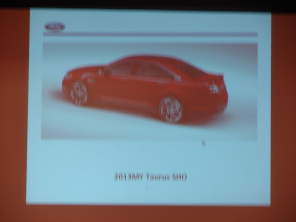 Red sedan, 3/4 front view, with text '2013MY Taurus SHO'
