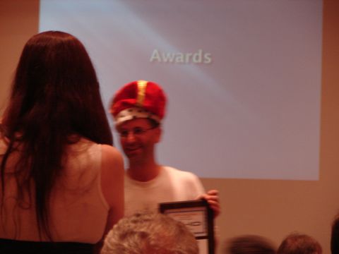 1992 Ford Taurus - A man in a crown holds a framed award at an event with 'Awards' projected on a screen.