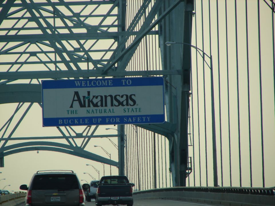 Arkansas welcome sign on bridge with traffic