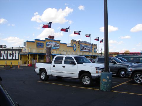 1992 Ford Taurus - A white pickup truck is parked in the lot of the Big Texas Steak Ranch, with Texas flags flying overhead.