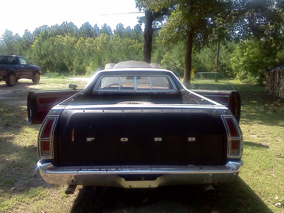 Rear view of black 1979 Ford Ranchero with doors open. Another truck is visible to the left
