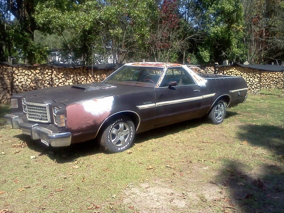 Dark brown 1977 Ford Ranchero with primer on front fender, parked on grass