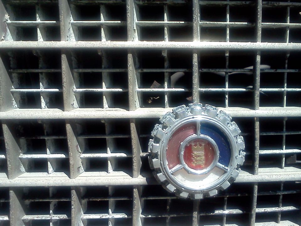 Close-up of a vehicle's front grille with a circular emblem red, white, and blue sections and a crown in the center