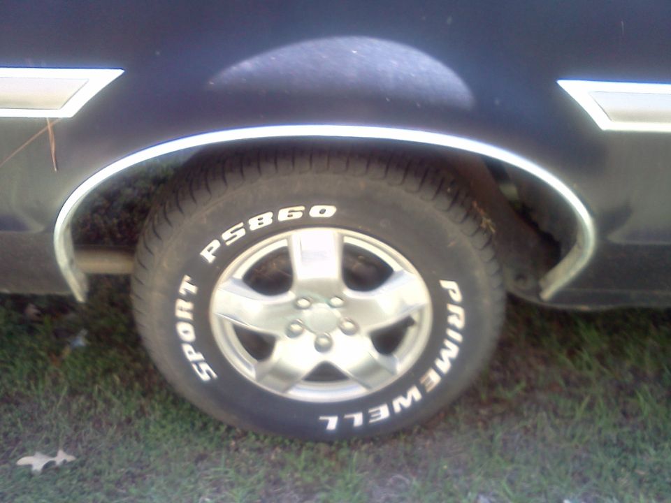 Wheel and fender detail of a dark vehicle with chrome trim