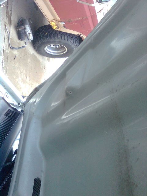 1984 Ford Bronco - Close-up view of a white SUV's fender and tire, possibly in a garage.